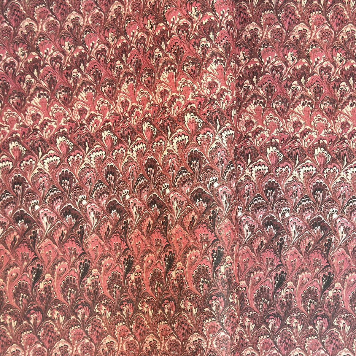 a sheet of Italian printed marbled paper with a marble design in pink, maroon and white