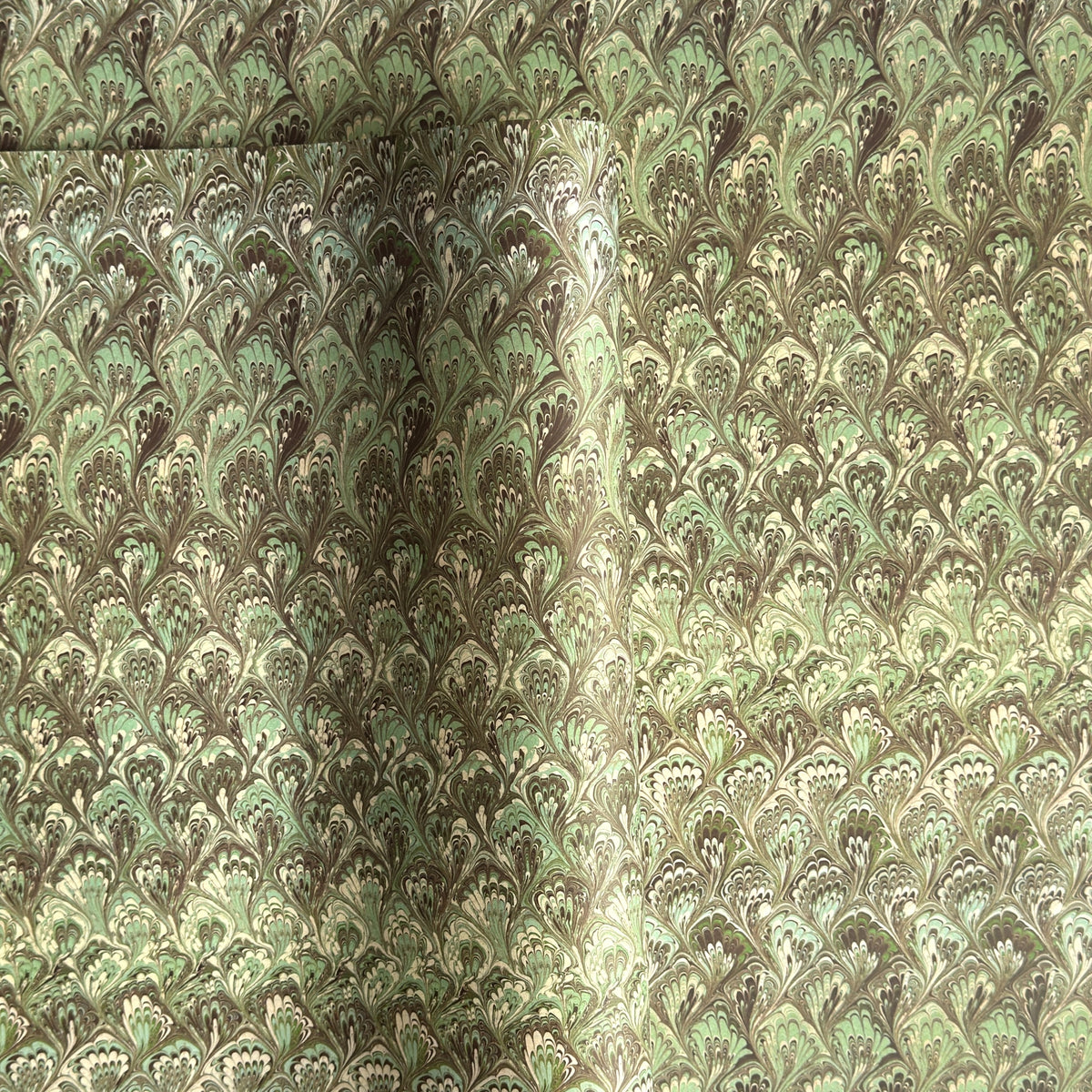 a sheet of Italian printed marbled paper by Tassotti with a marbled design in tones of green and cream