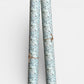 floral italian florentine wrapping paper with a white repeat floral on a mustard background. Pictured rolled