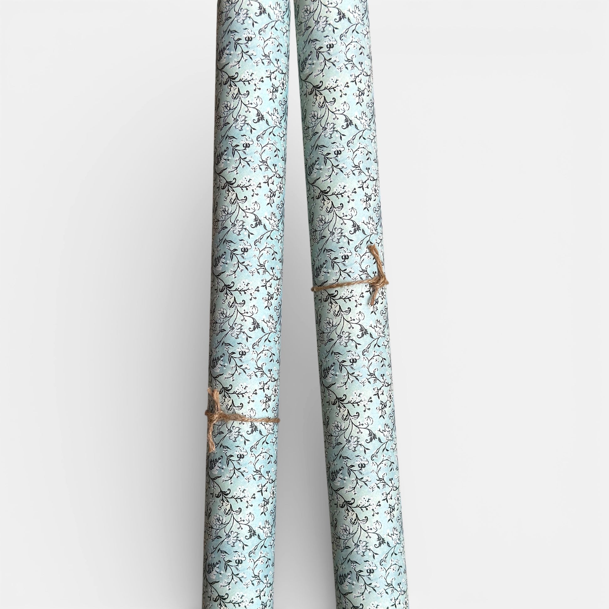 floral italian florentine wrapping paper with a white repeat floral on a mustard background. Pictured rolled