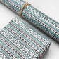 italian Remondini patterned wrapping paper by Tassotti. Striped design with bands of flowers in dark navy and teal on cream backdrop.  Shown as a present and also as a roll