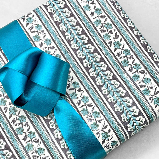 italian Remondini patterned wrapping paper by Tassotti. Striped design with bands of flowers in dark navy and teal on cream backdrop.  Close up