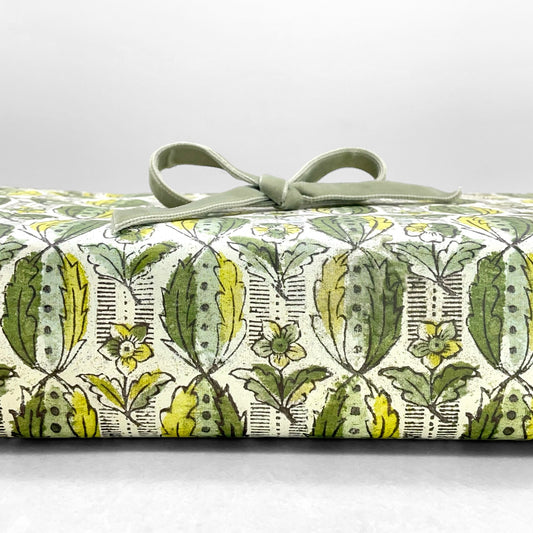 italian Remondini patterned wrapping paper by Tassotti. Block print style pattern with green leaves and flowers on a white background. Wrapped as a present with a green bow