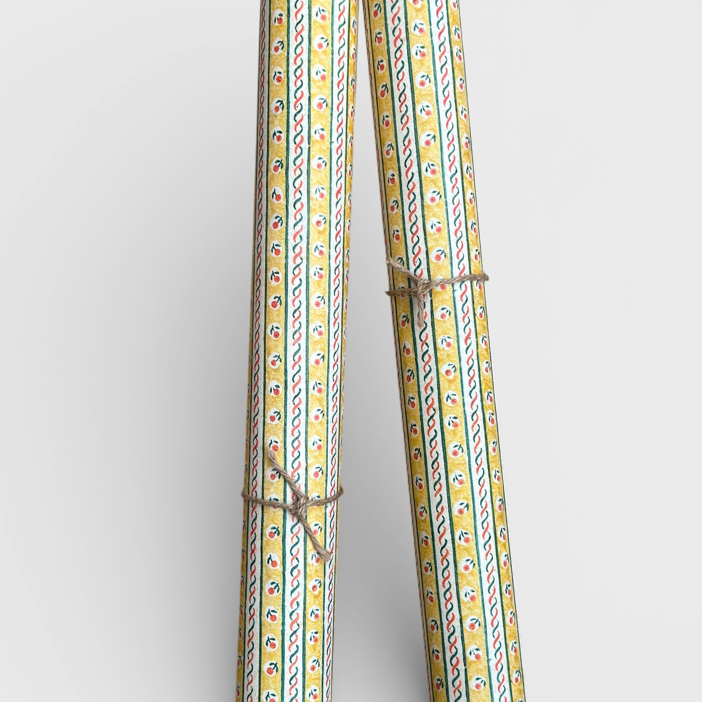 a sheet of florentine italian wrapping paper with a striped design in yellow, green, red and white with a little flower block print between the stripes. Pictured rolled