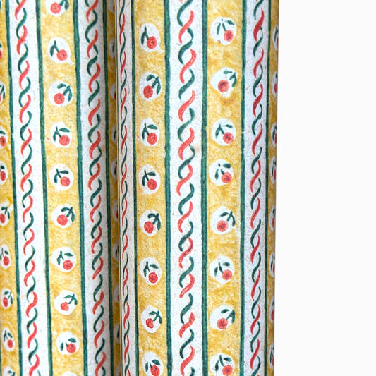 a sheet of florentine italian wrapping paper with a striped design in yellow, green, red and white with a little flower block print between the stripes