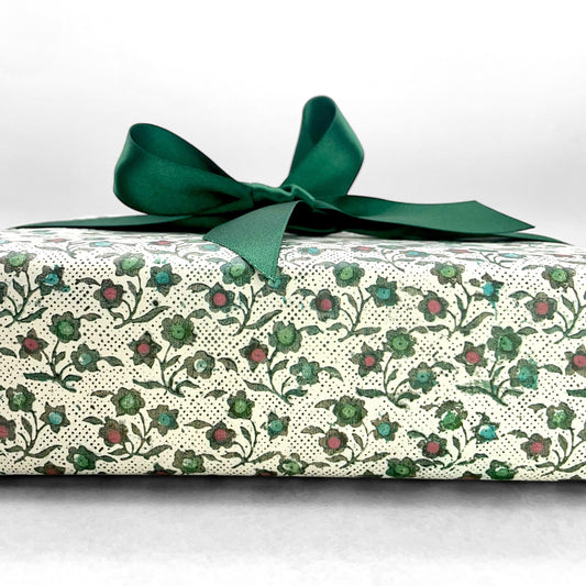 italian Remondini patterned wrapping paper by Tassotti. Little floral repeat pattern of block print style flowers in blue, red and green on a white background. Wrapped as a present with green bow