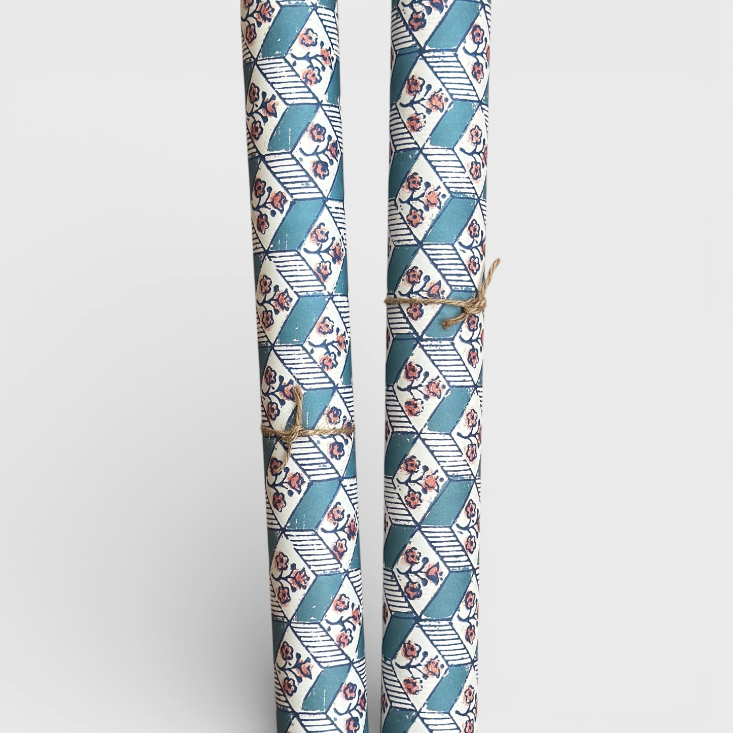 italian remondini florentine wrapping paper with a geometric rombi pattern in blue with a block print flower in pink on a white background. Picture rolled