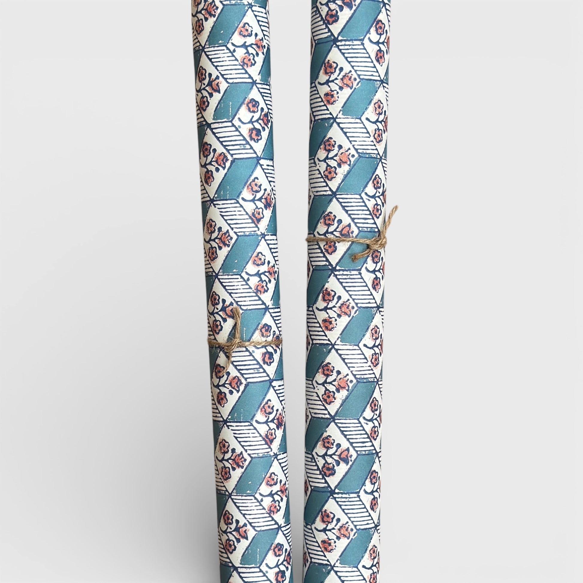 italian remondini florentine wrapping paper with a geometric rombi pattern in blue with a block print flower in pink on a white background. Picture rolled