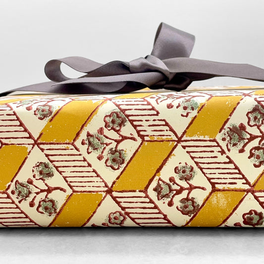 italian Remondini patterned wrapping paper by Tassotti. Block printed rhombus pattern with little flowers in yellow, white and green. Wrapped as a present with a grey ribbon bow