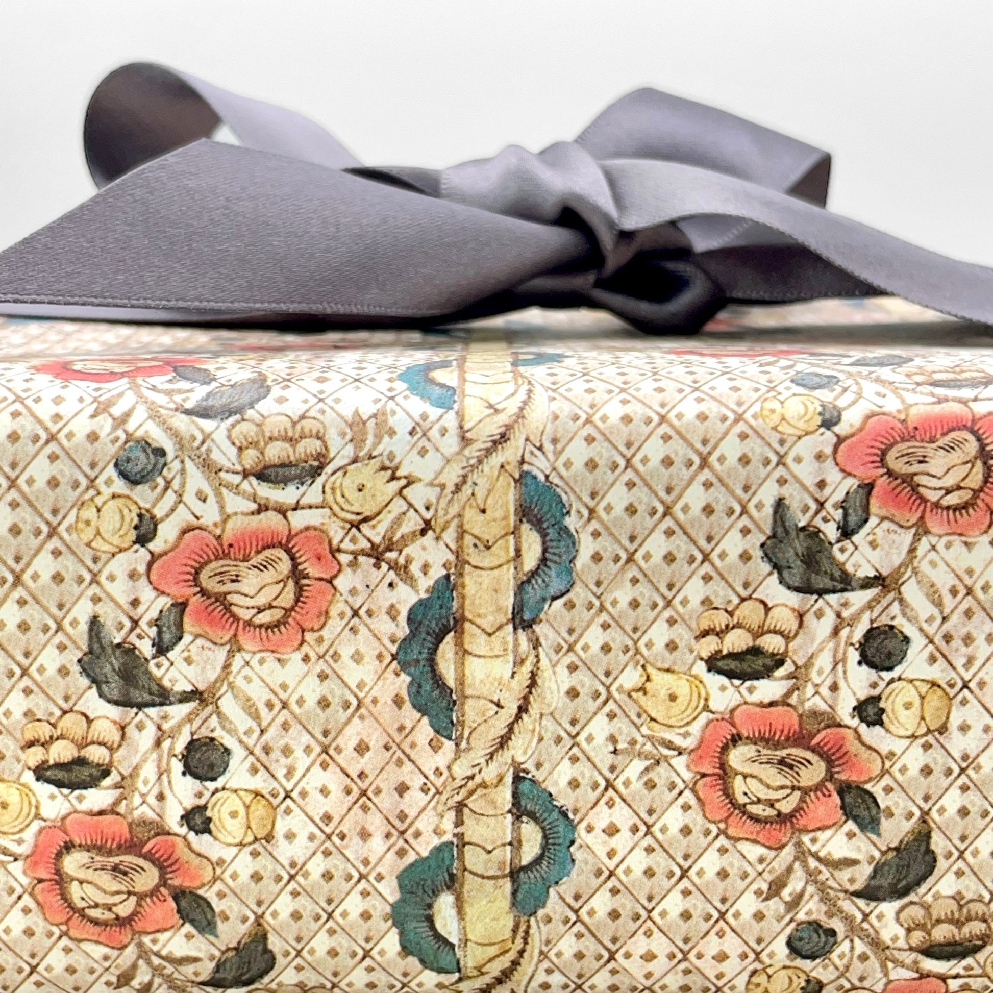 Remondini Italian patterned wrapping paper by Tassotti, A detailed trellis design with flowers in taupe, rose and aqua colours. Pictured wrapped with a grey ribbon bow. Close up
