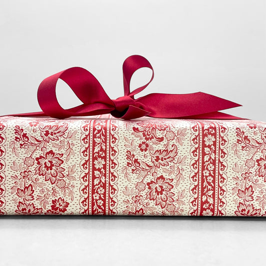 italian Remondini patterned wrapping paper by Tassotti. A delicate broccate pattern in red on cream. Pictured as a present with a red ribbon bow