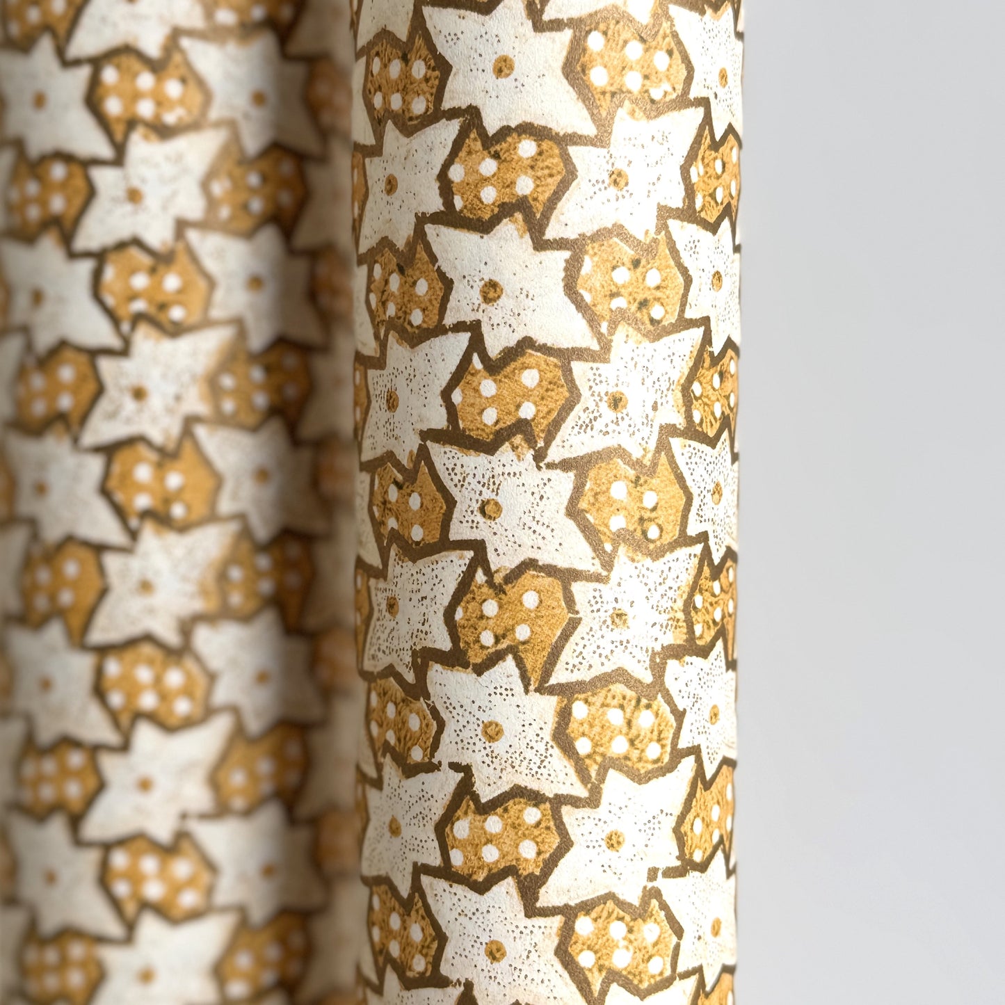 a sheet of italian wrapping paper with a star pattern in yellow, gold and white. Close up
