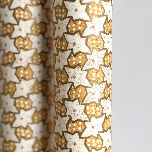 a sheet of italian wrapping paper with a star pattern in yellow, gold and white. Close up