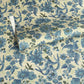 a sheet of wrapping paper by The Kensington Paperie with a large chintz floral in teal blue, with green foliage and a speckled light green ground 