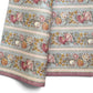 A floral patterned wrapping paper with large flowers in pink, cream, yellow, and muted green on a pale blue-gray background, divided by narrow decorative borders.