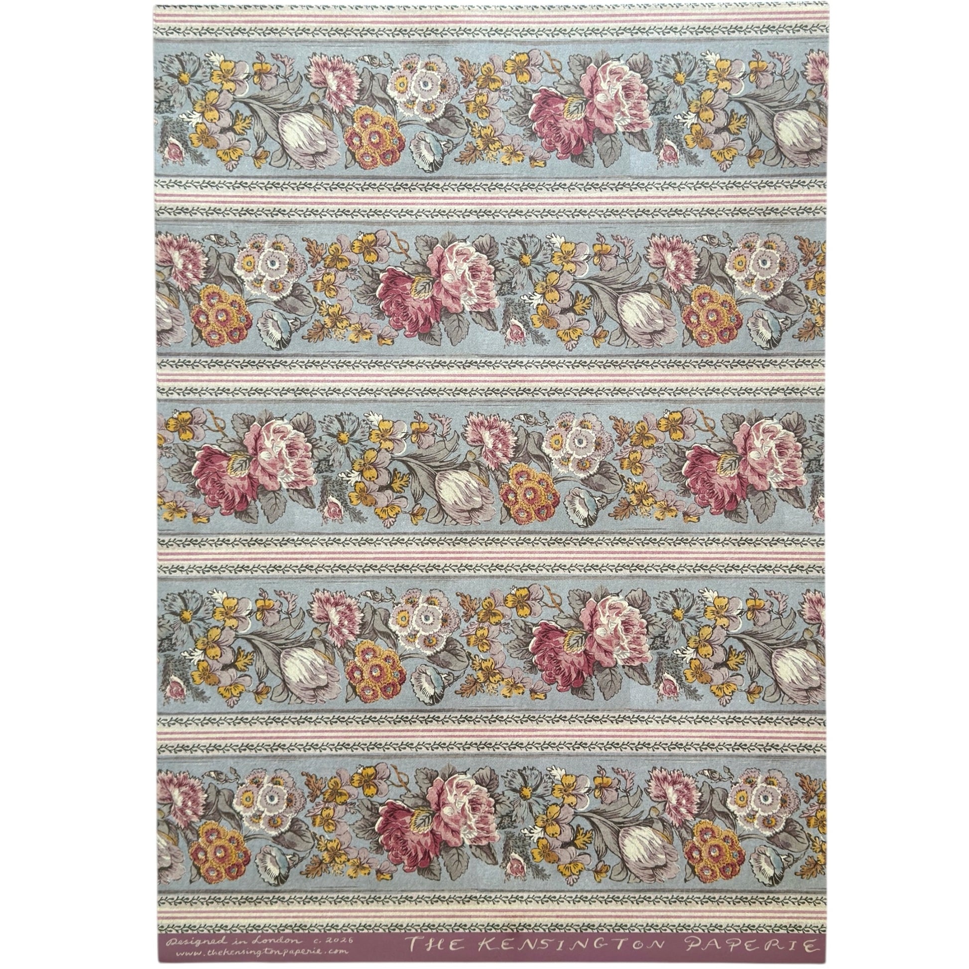 A floral patterned wrapping paper with large flowers in pink, cream, yellow, and muted green on a pale blue-gray background, divided by narrow decorative borders.