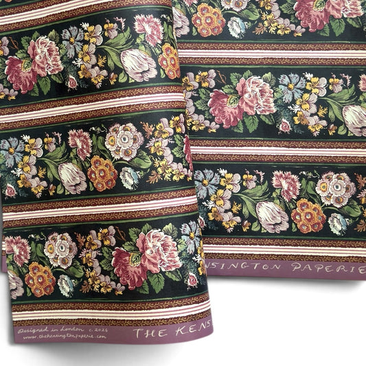 A sheet of wrapping paper, showing a detailed pattern of pink, white, and yellow flowers with green leaves on a black, bordered by horizontal stripes in pink, white, and brown.