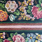 A sheet of wrapping paper, showing a detailed pattern of pink, white, and yellow flowers with green leaves on a black, bordered by horizontal stripes in pink, white, and brown.