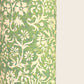 A sheet of green wrapping paper with a dense cream floral and vine pattern, shown partially unrolled on a white background. 