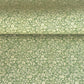 A sheet of green wrapping paper with a dense cream floral and vine pattern, shown partially unrolled on a white background. 