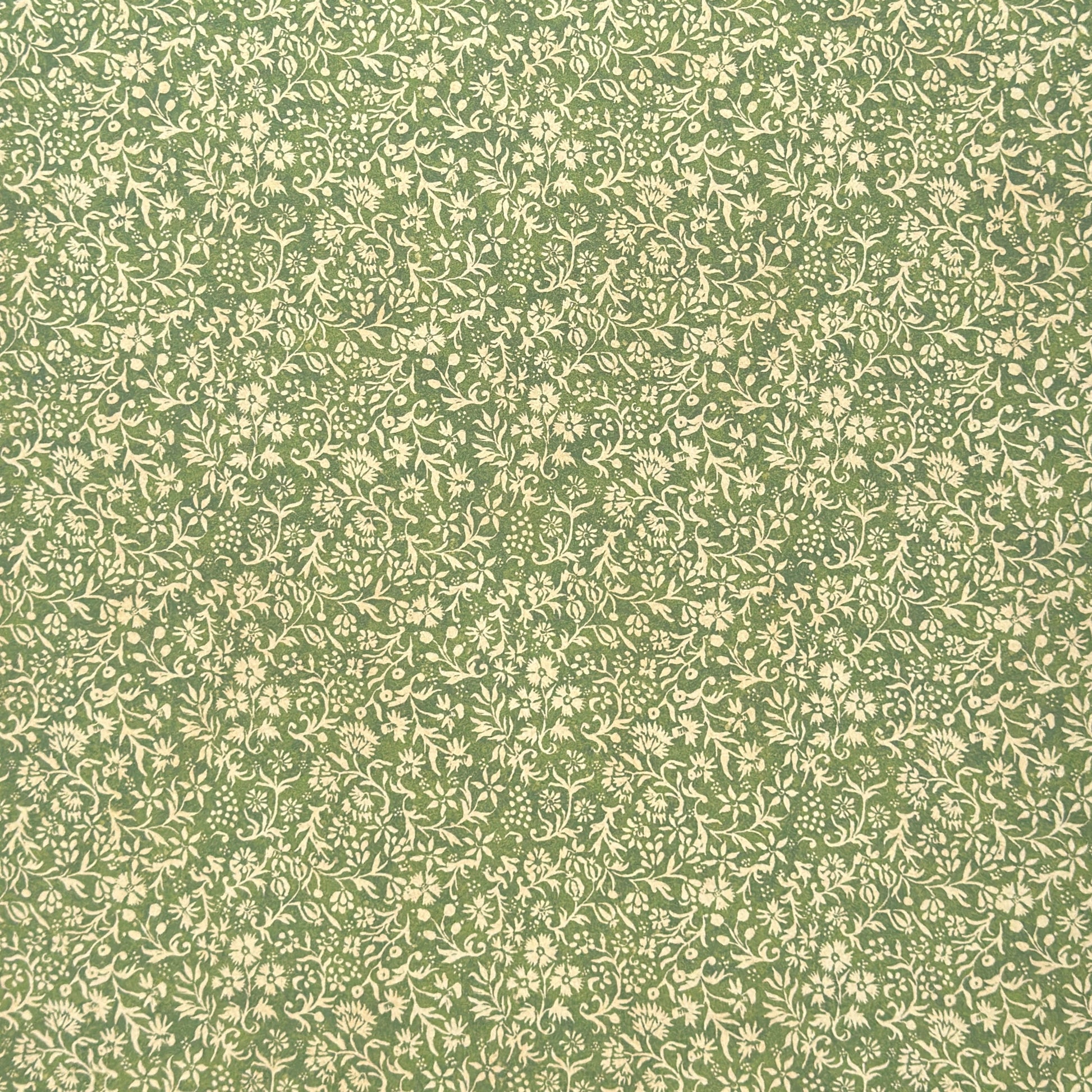 A sheet of green wrapping paper with a dense cream floral and vine pattern, shown partially unrolled on a white background. 
