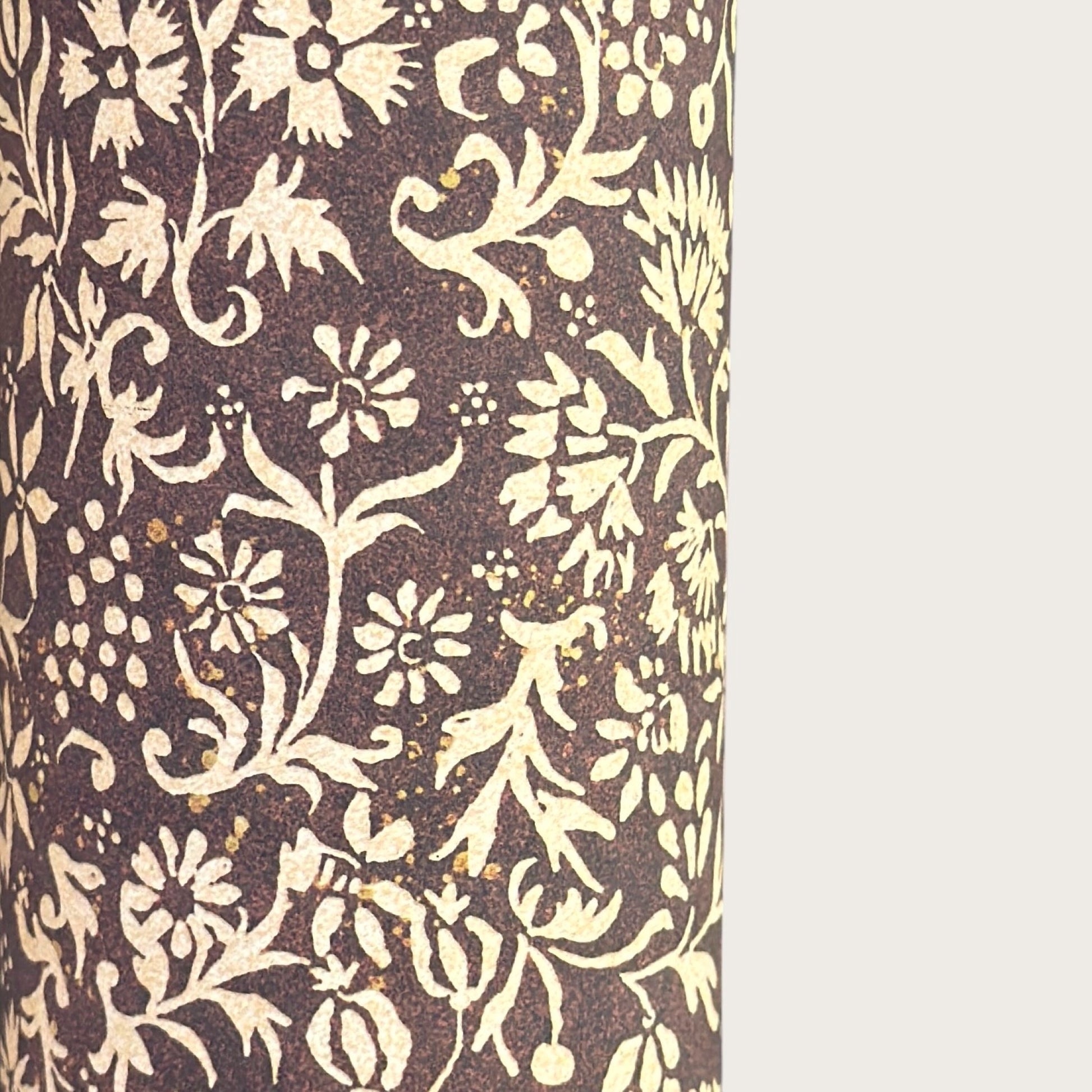 A sheet of dark aubergine wrapping paper with a dense cream floral and vine pattern