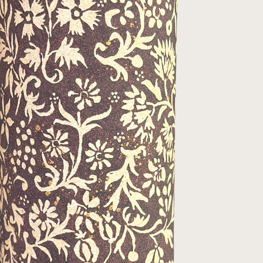 A sheet of dark aubergine wrapping paper with a dense cream floral and vine pattern