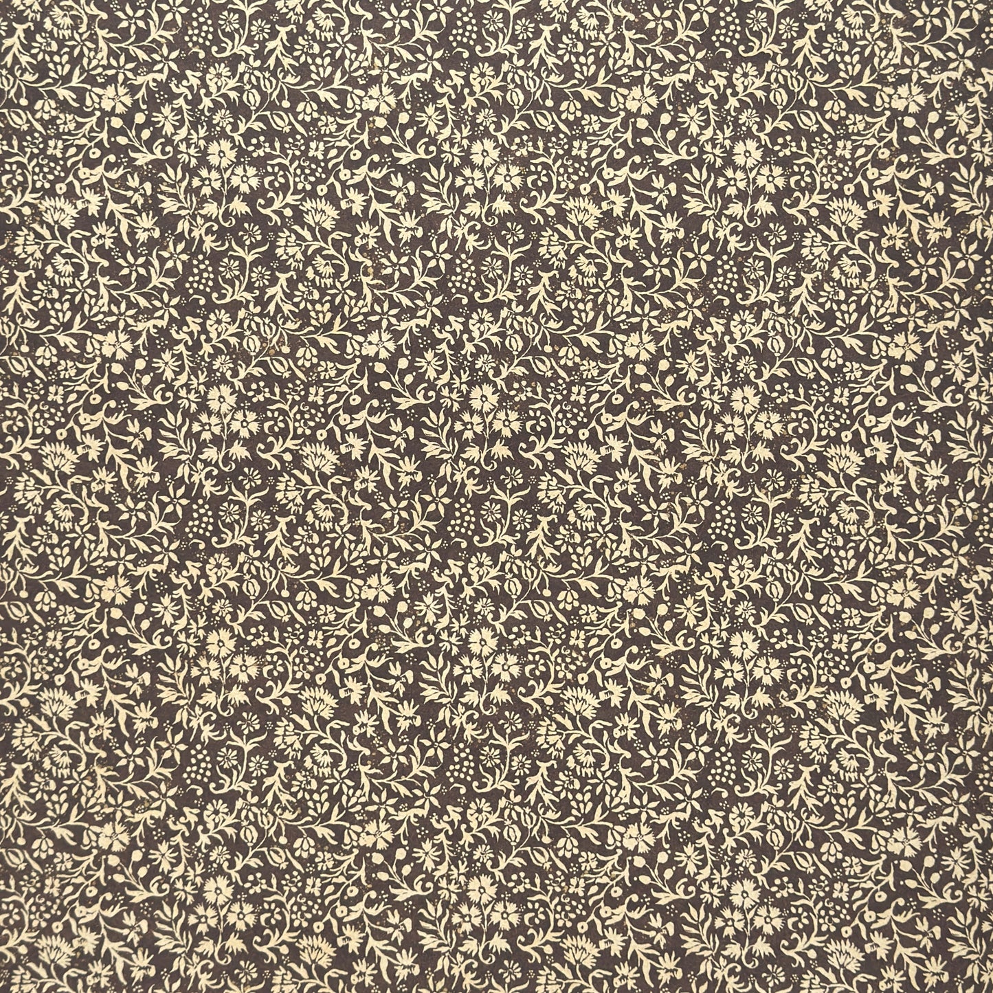 A sheet of dark aubergine wrapping paper with a dense cream floral and vine pattern