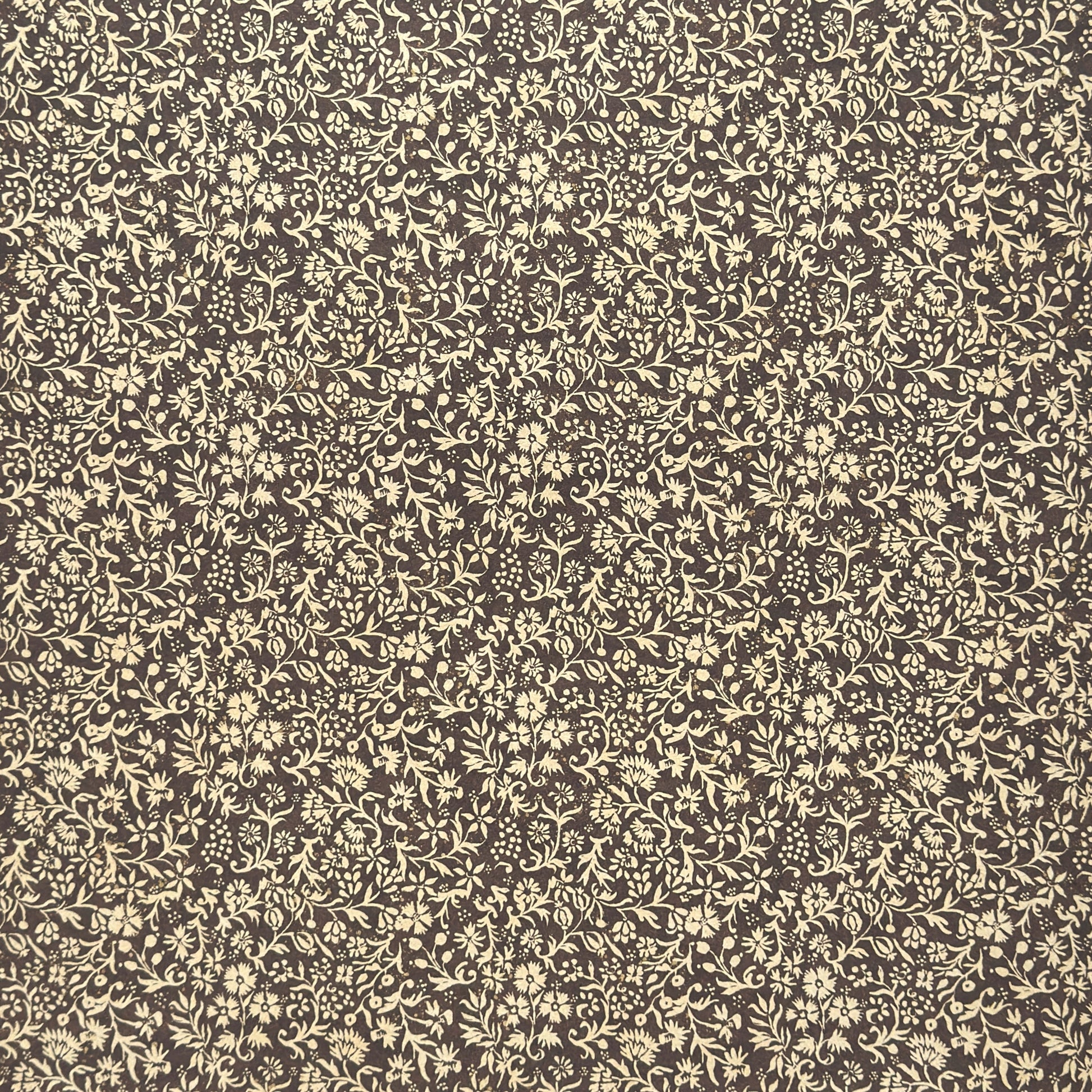 A sheet of dark aubergine wrapping paper with a dense cream floral and vine pattern