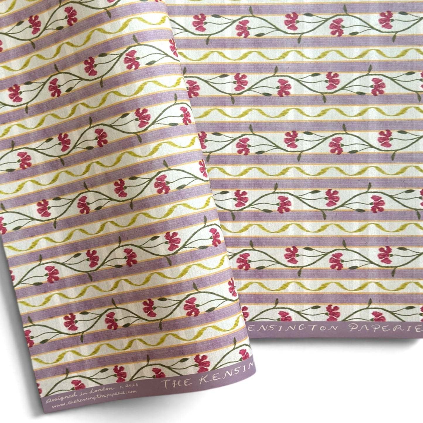 A close-up of patterned paper with horizontal lavender stripes, small pink flowers, and green stems. 