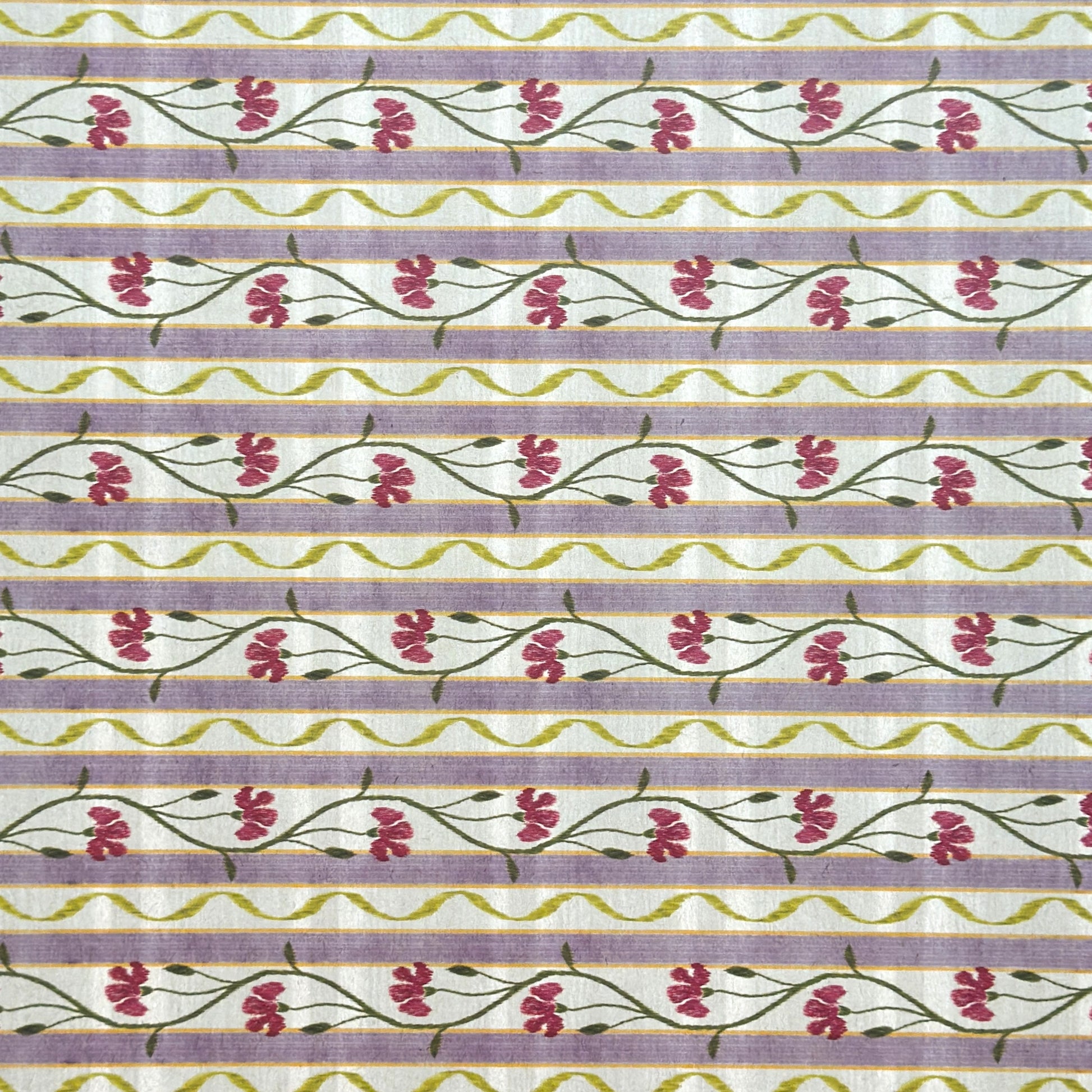 A close-up of a patterned wrapping paper featuring horizontal lavender and cream stripes with pink flowers, green stems, and olive-green wavy lines.