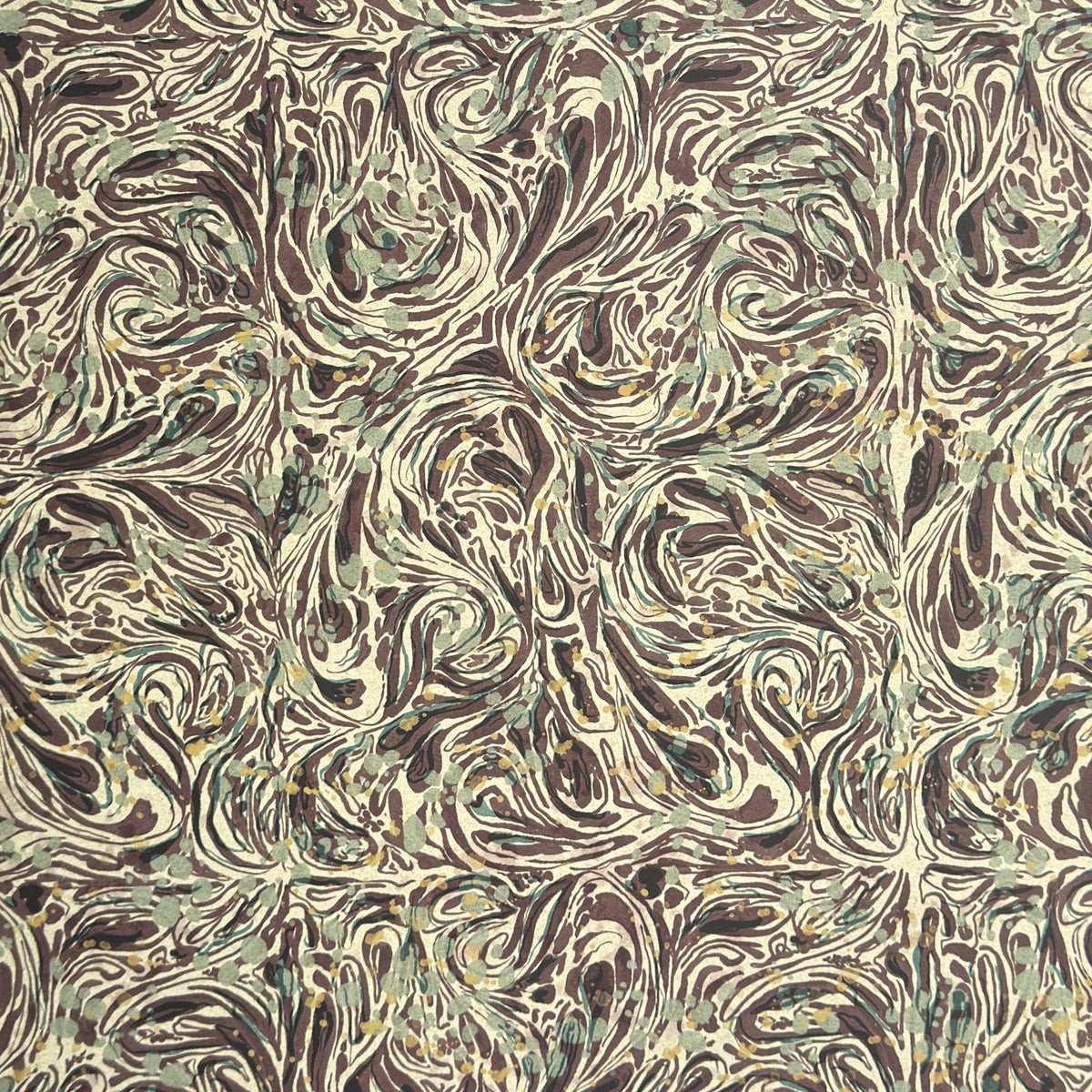 a printed marbled wrapping paper sheet with swirling brown, beige, muted green, and small yellow accents. By The Kensington Paperie brand