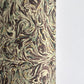 A close-up of a printed marbled wrapping paper sheet with swirling brown, beige, muted green, and small yellow accents. By The Kensington Paperie brand
