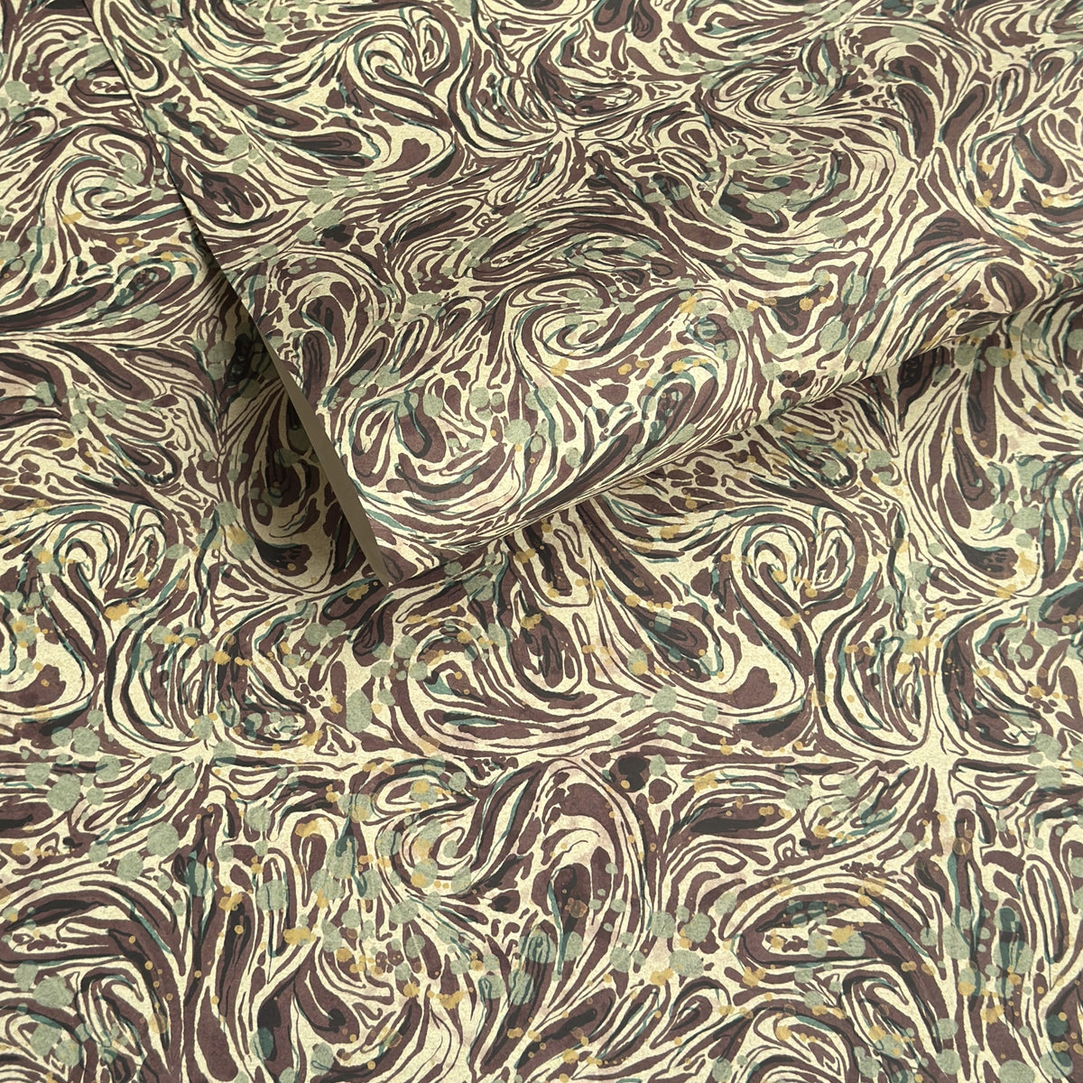 a printed marbled wrapping paper sheet with swirling brown, beige, muted green, and small yellow accents. By The Kensington Paperie brand