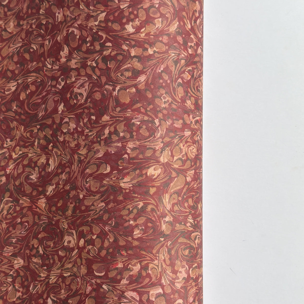 a marbled patterned wrapping paper with swirling abstract swirls in reddish brown, rust, beige, and muted gold tones.