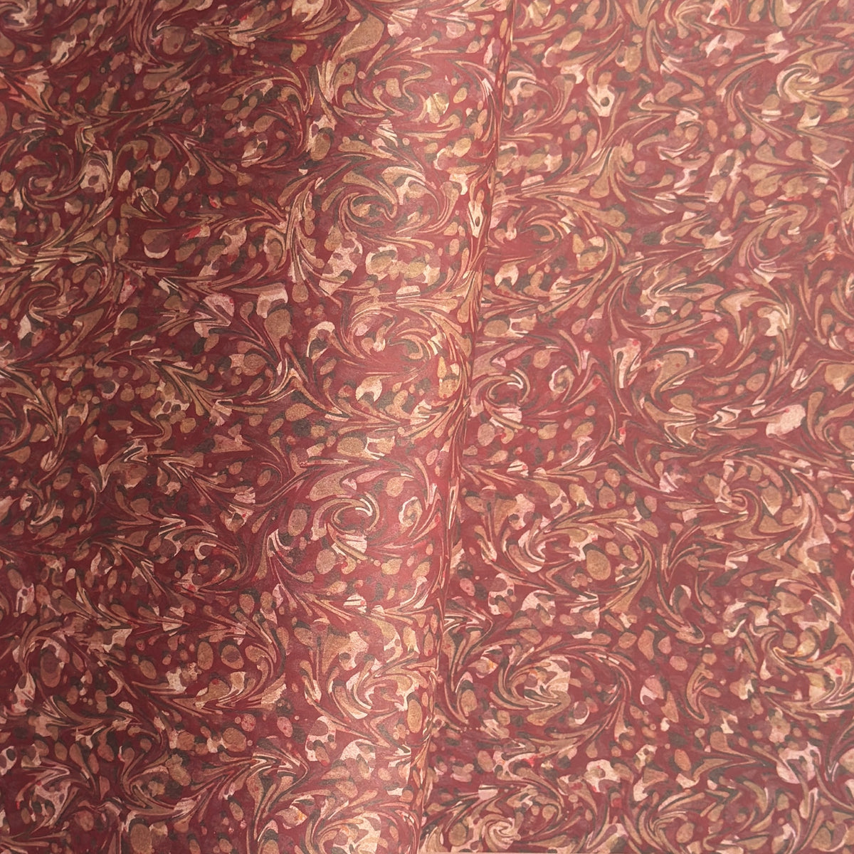 a marbled patterned wrapping paper with swirling abstract swirls in reddish brown, rust, beige, and muted gold tones.