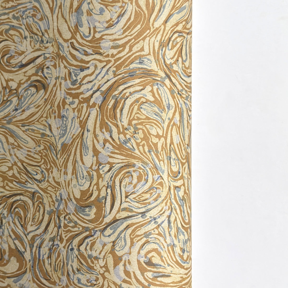 a sheet of printed marbled wrapping paper by The Kensington Paperie with a marbled swirl pattern in mustard, grey and cream