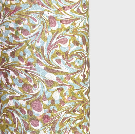A close-up of a marbled patterned paper with swirling abstract swirls in muted gold, dusty pink, pale blue, and off-white, shown against a light gray background.