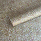 A close-up of patterned paper with an intricate marbled swirl design in olive green, gold, white, and dusty pink, with one corner folded over to show the paper's thickness.