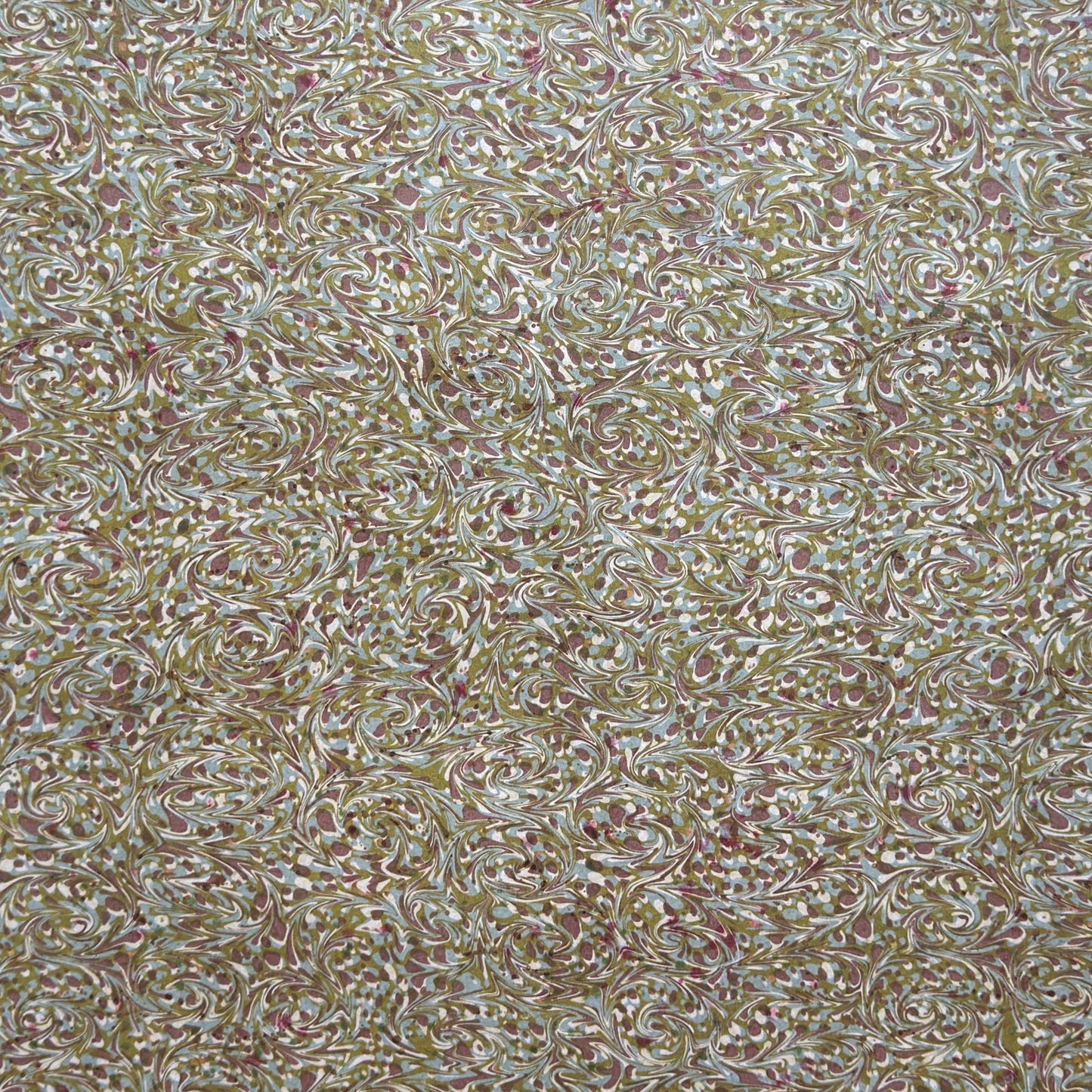 A close-up of a marbled patterned material with swirling beige, white, olive green, and muted pink tones filling the frame.