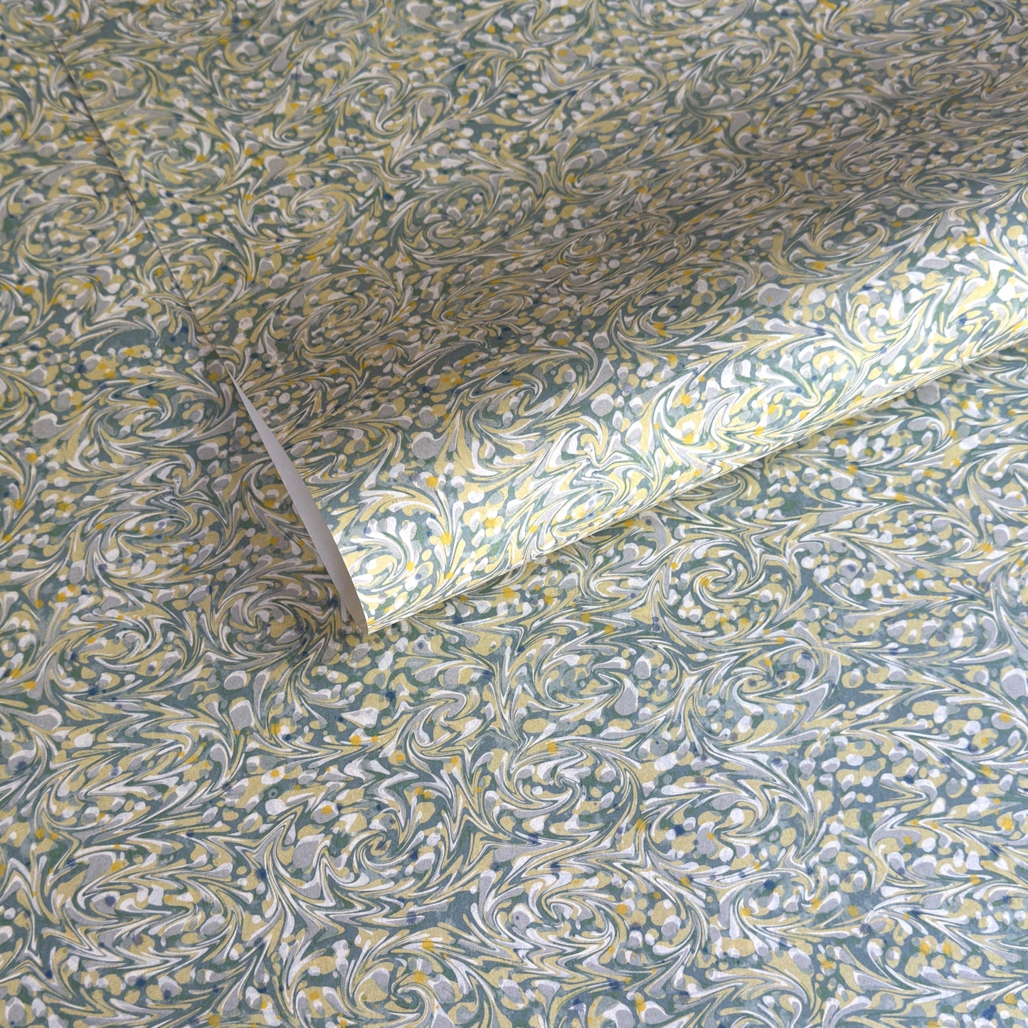 a sheet of printed marbled paper with a marble pattern in sage green, butter yellow, soft grey and white. 
