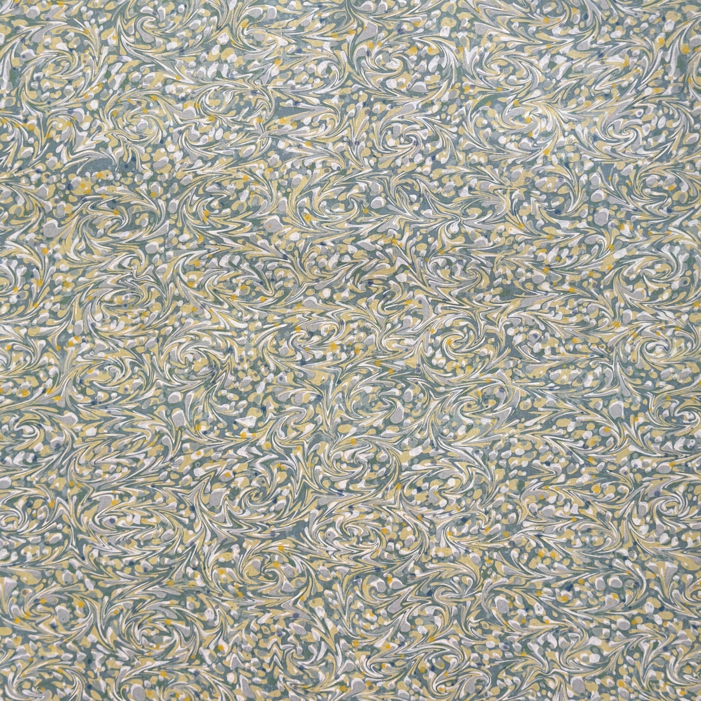 a sheet of printed marbled paper with a marble pattern in sage green, butter yellow, soft grey and white. 
