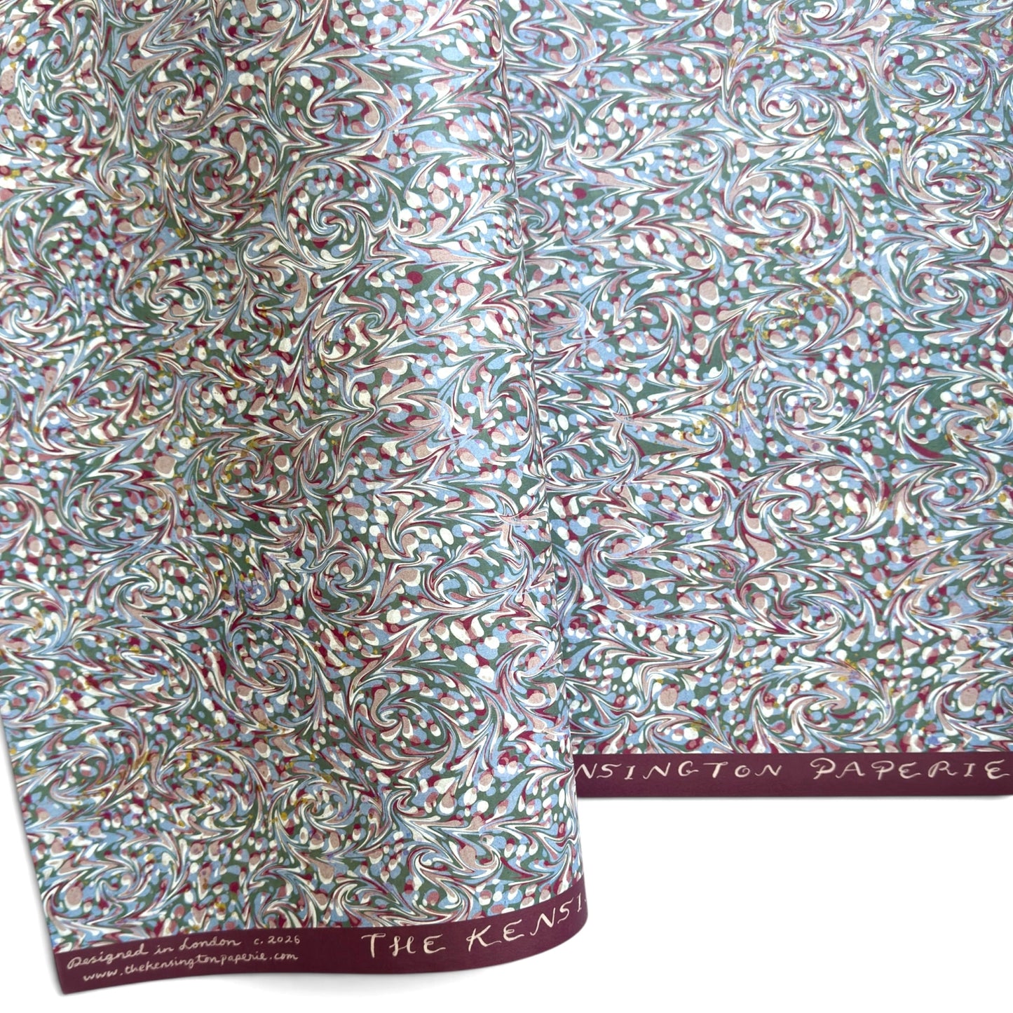 A close-up of patterned paper with an intricate swirling marbled design in white, blue, green, and burgundy.