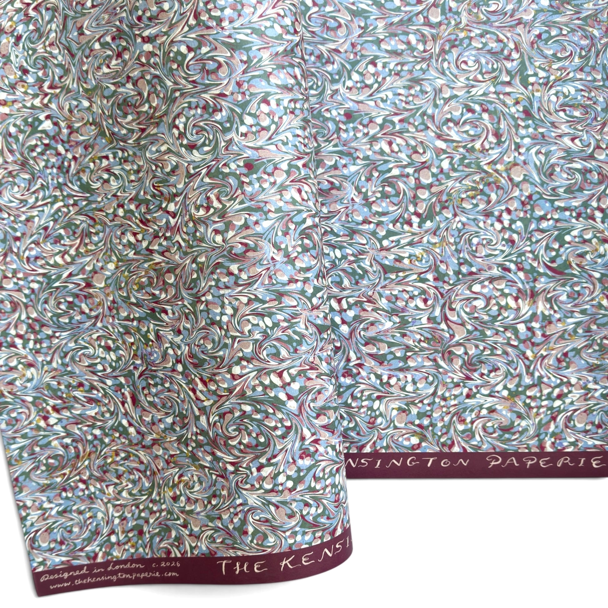 A close-up of patterned paper with an intricate swirling marbled design in white, blue, green, and burgundy.