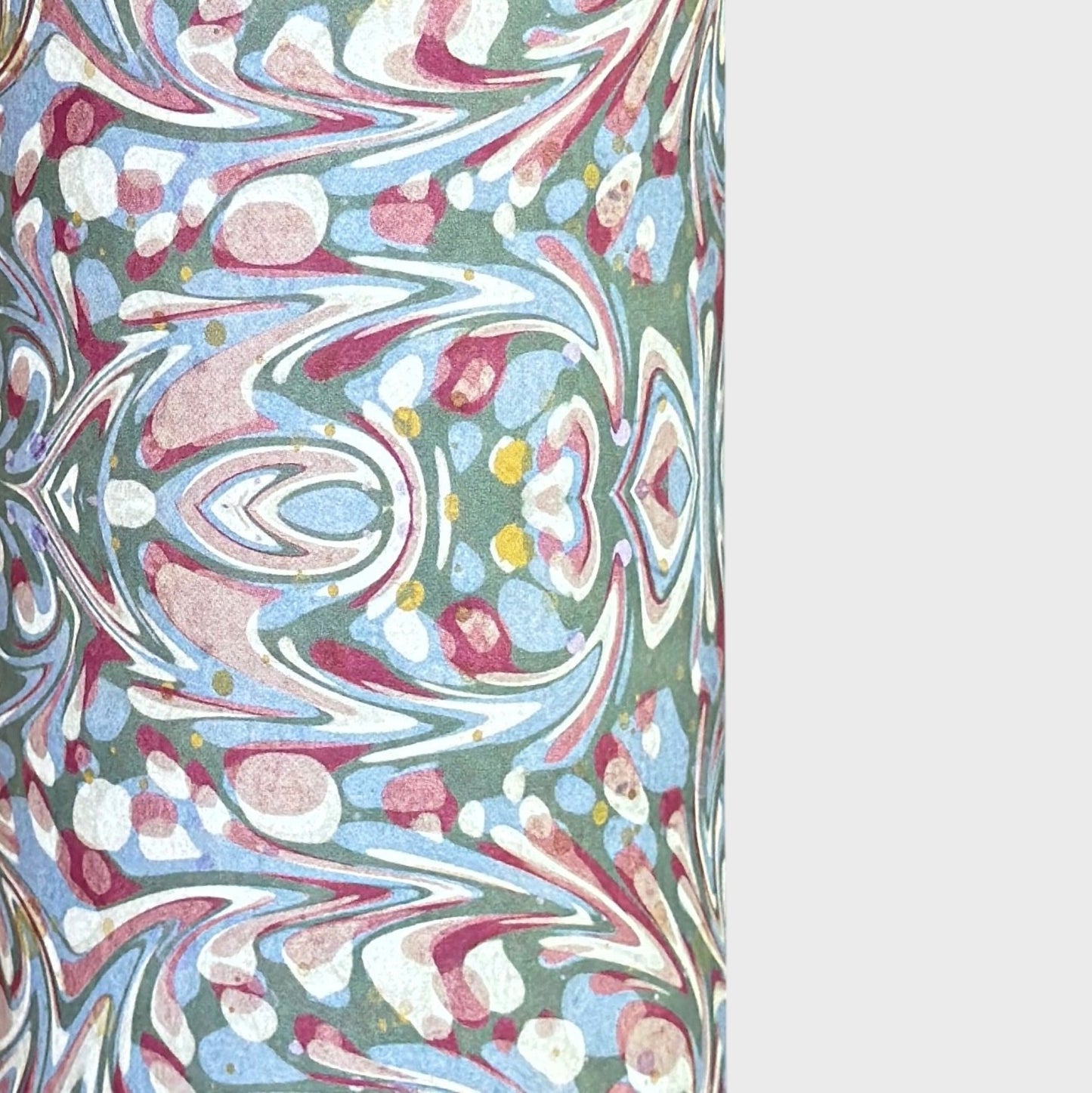A close-up of patterned paper with an intricate swirling marbled design in white, blue, green, and burgundy.
