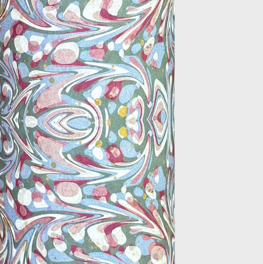 A close-up of patterned paper with an intricate swirling marbled design in white, blue, green, and burgundy.