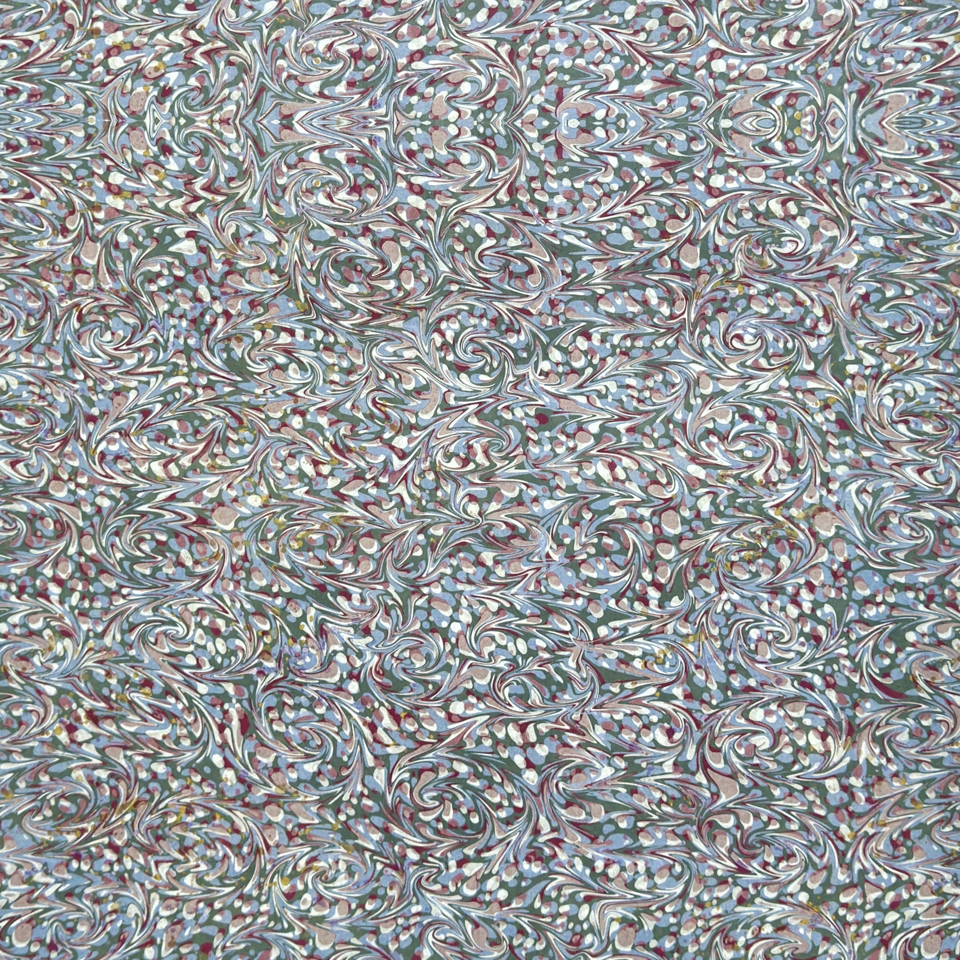 A close-up of patterned paper with an intricate swirling marbled design in white, blue, green, and burgundy.