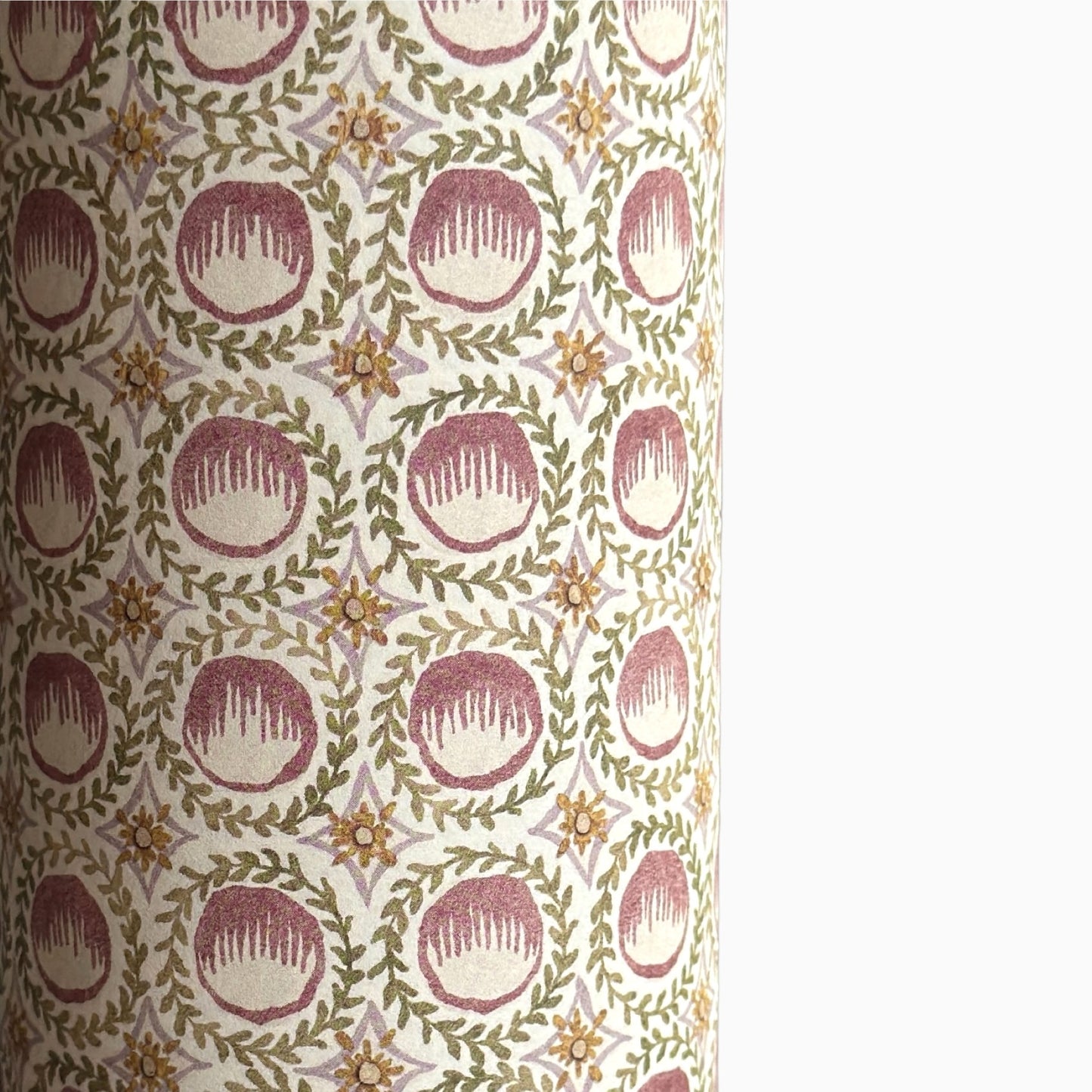 close up of a sheet of wrapping paper with a block printed design of rows of English steam puddings in pink