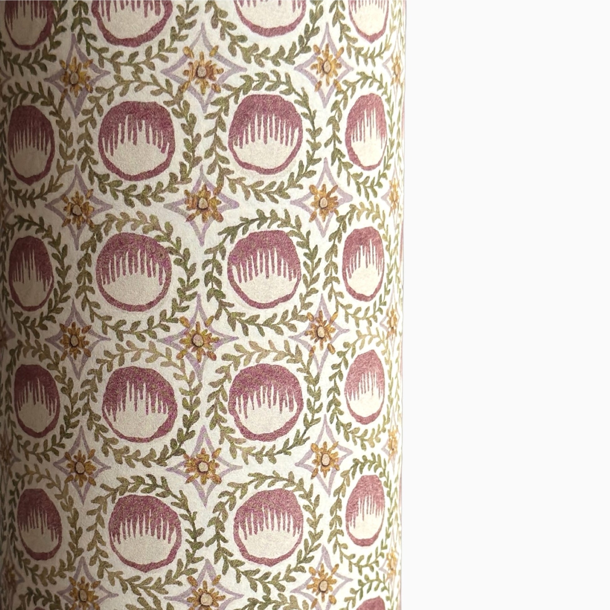 close up of a sheet of wrapping paper with a block printed design of rows of English steam puddings in pink