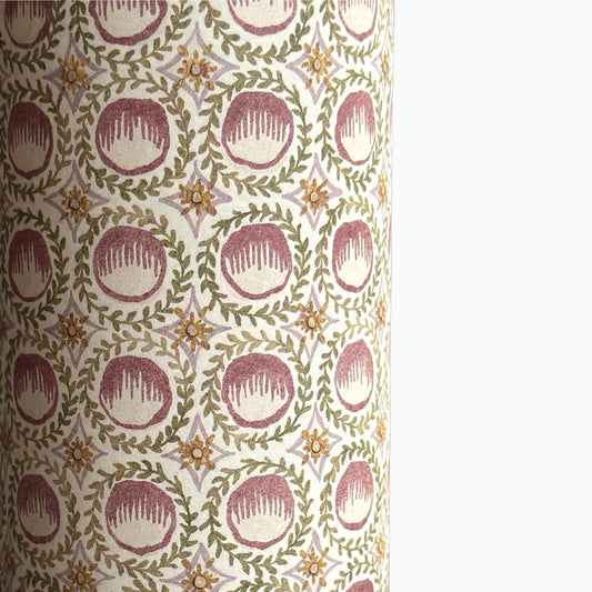 close up of a sheet of wrapping paper with a block printed design of rows of English steam puddings in pink